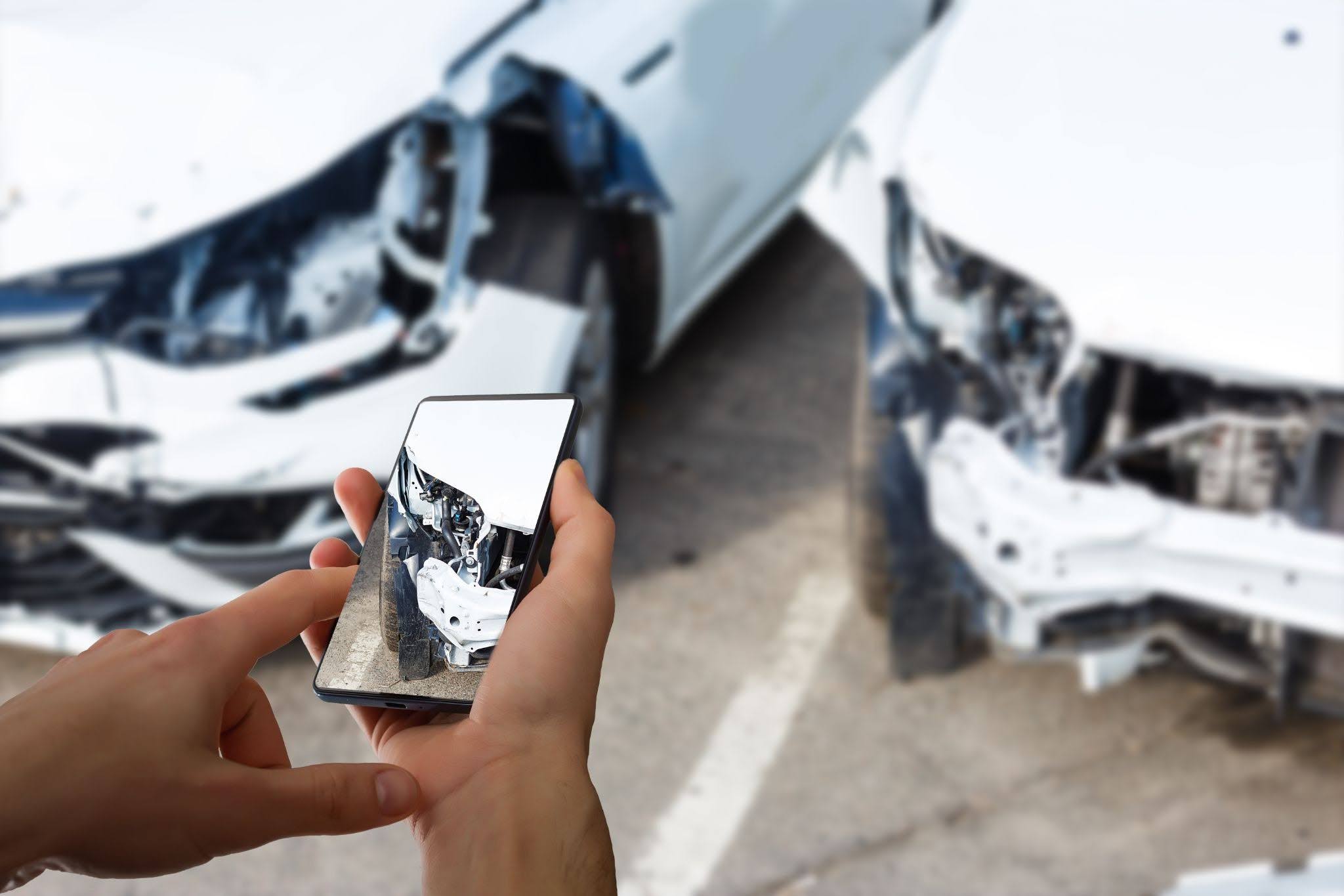 A man taking a picture of his car after an accident