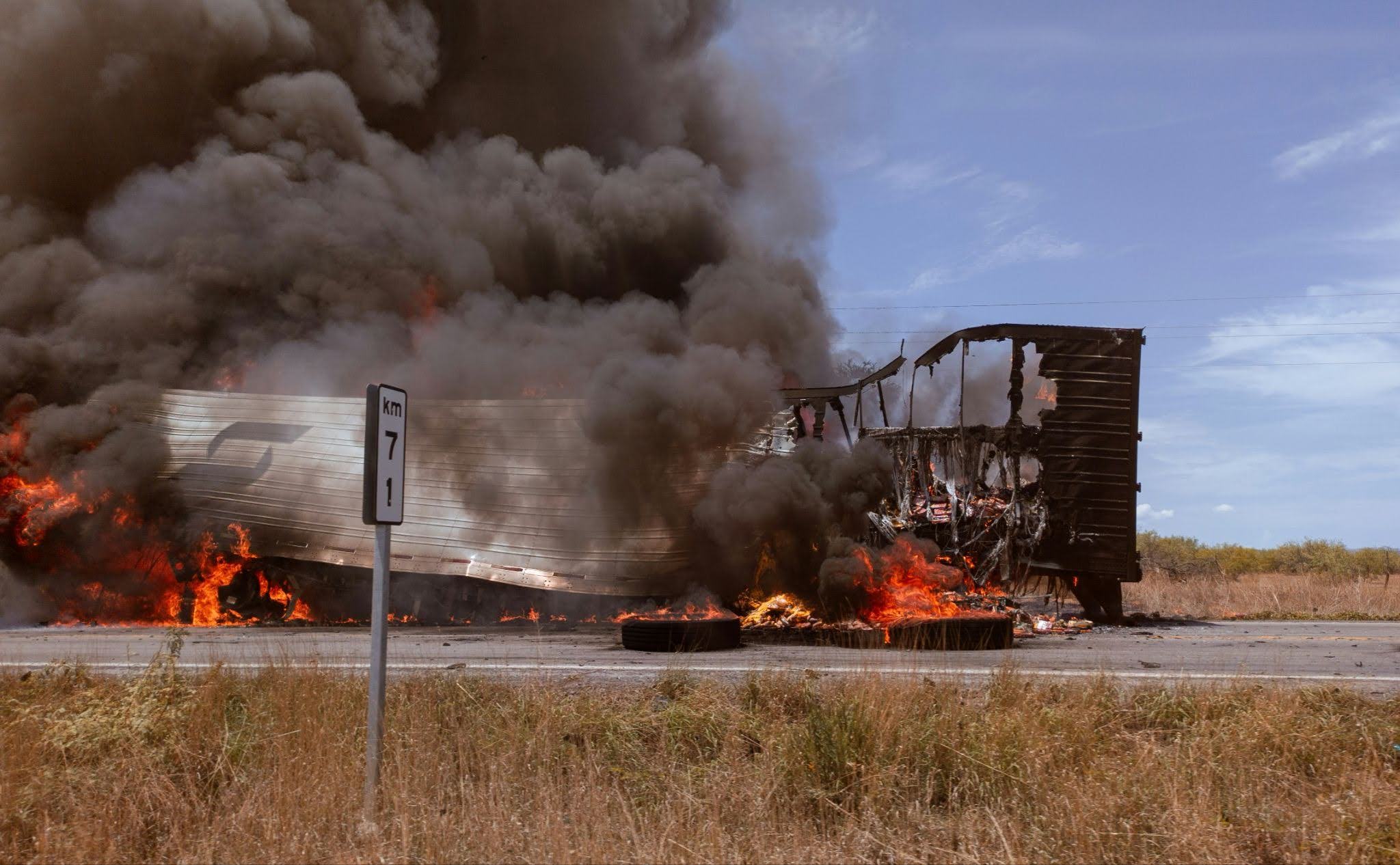 A truck on fire on the road.